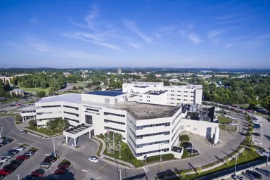 Aerial view of a modern hospital building surrounded by parking and greenery